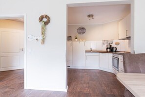 Une cuisine moderne avec des meubles blancs, un plan de travail en bois et un four encastré.