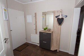 A room with a wooden dresser, a mirror, a radiator, and a door with a heart-shaped decoration. - Holiday apartment with 1 bedroom (Bad Zwischenahn)
