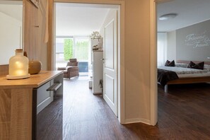 A modern bedroom with a bed, a bedside table, and a view of a balcony. - Holiday apartment with 1 bedroom (Bad Zwischenahn)