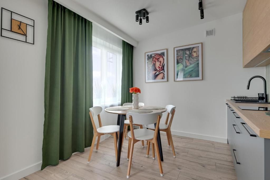 Una cocina moderna con comedor, que incluye una mesa redonda con sillas, un reloj en la pared y obras de arte.