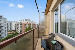 A balcony with a table and chairs, overlooking a residential area with modern buildings. - Apartament Tamara by Q4 Apartments  (Gdańsk)