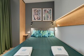 A hotel room with a bed, green curtains, a headboard, two framed pictures, and a nightstand. - Apartament Tamara by Q4 Apartments  (Gdańsk)