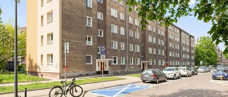A multi-story residential building with a parking area and a bicycle parked outside.