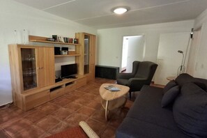 Ein Wohnzimmer mit einer Couch, einem Fernseher, einer Holzkabine und einem kleinen Tisch.