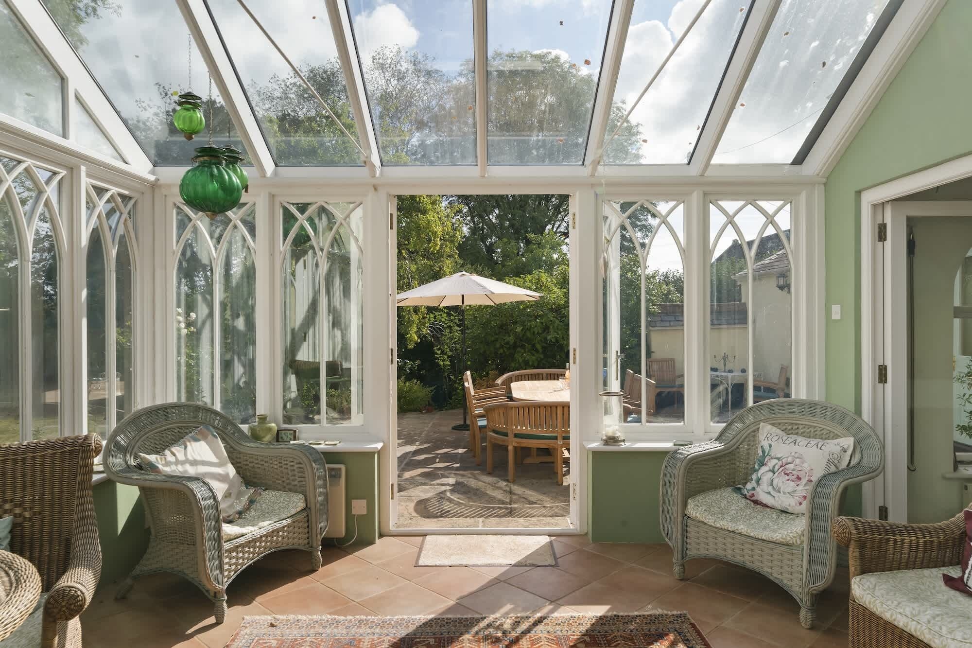 A conservatory with wicker furniture, a table, and chairs.