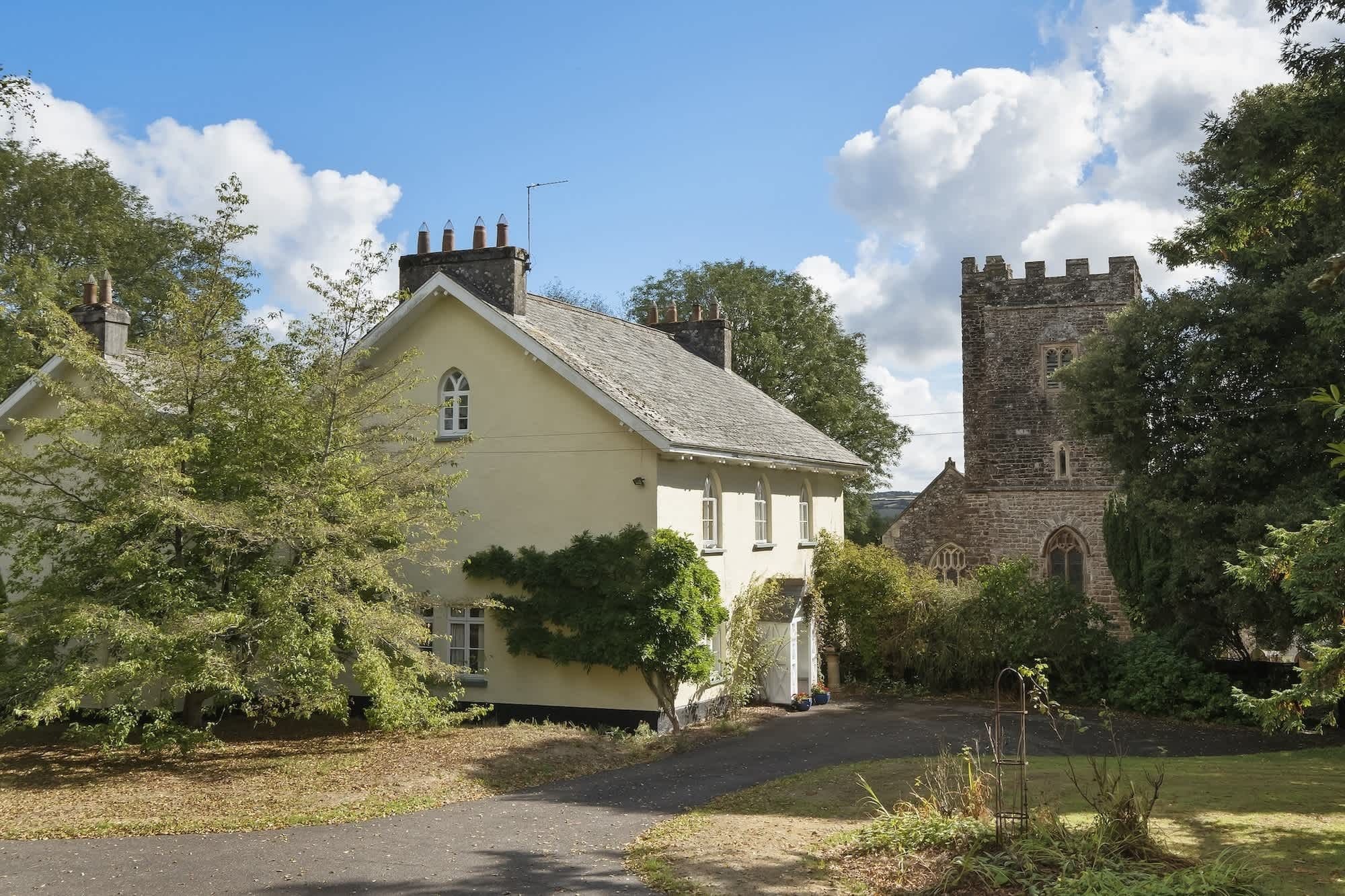 A traditional house with a tower, surrounded by trees and a clear sky.