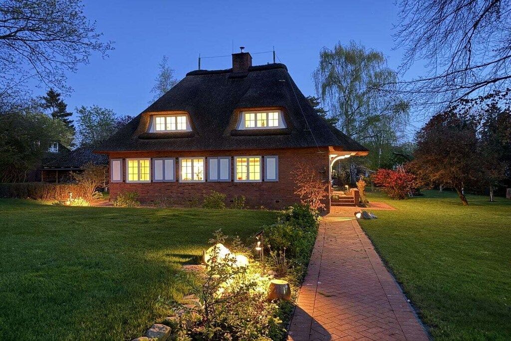 Une maison à deux étages avec une façade en briques, de grandes fenêtres et une pelouse bien entretenue.