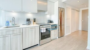 Una cocina moderna con armarios blancos, un refrigerador de acero inoxidable, un horno y un microondas.