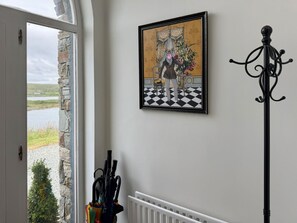 Een kamer met uitzicht op een meer, een lijst met een foto aan de muur en een kapstok.