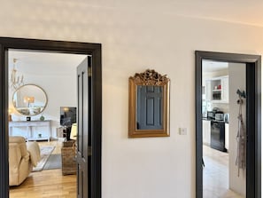 A hallway with a mirror, a door, and a view into a living room with a sofa and a lamp. - Cottage 516 - Clifden - sleeps 6 guests  in 3 bedrooms (Clifden)