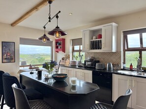 A modern kitchen with a central island, white cabinetry, and a view of the countryside. - Cottage 516 - Clifden - sleeps 6 guests  in 3 bedrooms (Clifden)