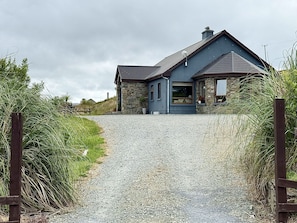 Een huis met een grindpad dat leidt naar een houten poort.