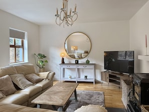 A living room with a sofa, coffee table, TV, fireplace, and a mirror on the wall. - Cottage 516 - Clifden - sleeps 6 guests  in 3 bedrooms (Clifden)