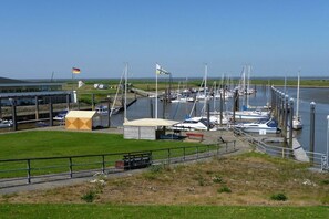 A marina with boats docked, a grassy area, and a building with a flag. - Holiday home with 1 bedroom (Otterndorf)