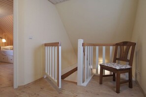 A bedroom with a wooden bed, a nightstand, and a chair. - Holiday home with 2 bedrooms (Gross Schwansee)