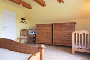A bedroom with a wooden bed, a wooden dresser, a chair, and a crib. - Holiday home with 2 bedrooms (Gross Schwansee)