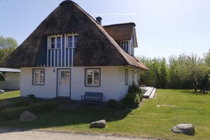 A traditional house with a thatched roof, a front door, and a bench outside. - Holiday home with 2 bedrooms (Gross Schwansee)