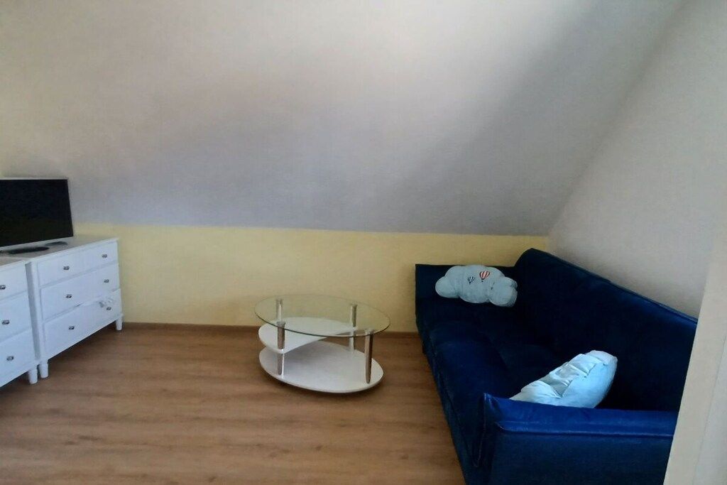Ett rum med en vit byrå, ett glasbord, en blå soffa och en tv som står på byrån.