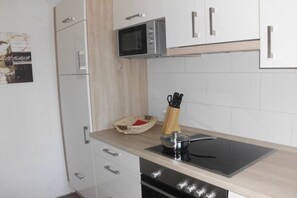 A modern kitchen with white cabinets, a microwave, a stove, and a sink. - Holiday home with 4 bedrooms (Hooksiel Wangerland)