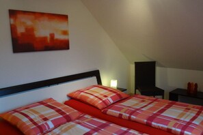 A bedroom with a bed, a nightstand, a chair, and a painting on the wall. - Holiday home with 3 bedrooms (Boltenhagen)