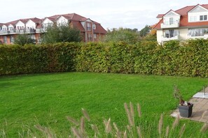 A residential area with a well-maintained lawn, a hedge, and houses with red-tiled roofs. - Holiday home with 3 bedrooms (Boltenhagen)