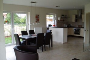 A modern kitchen with a dining area, large windows, and a view of the outdoors. - Holiday home with 3 bedrooms (Boltenhagen)