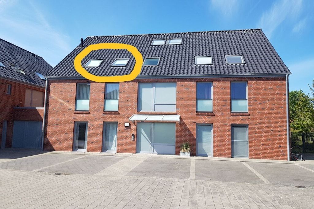 Ein zweistöckiges Backsteingebäude mit flachem Dach, zahlreichen Fenstern und einer Garagentür.