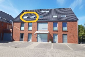 Ein zweistöckiges Backsteingebäude mit flachem Dach, zahlreichen Fenstern und einer Garagentür.