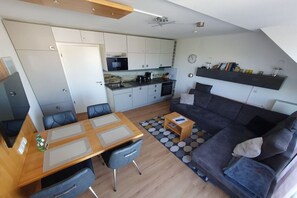 A compact living space with a kitchenette, a dining area, and a seating area with a sofa and a coffee table. - Holiday apartment with 2 bedrooms (Norderney)