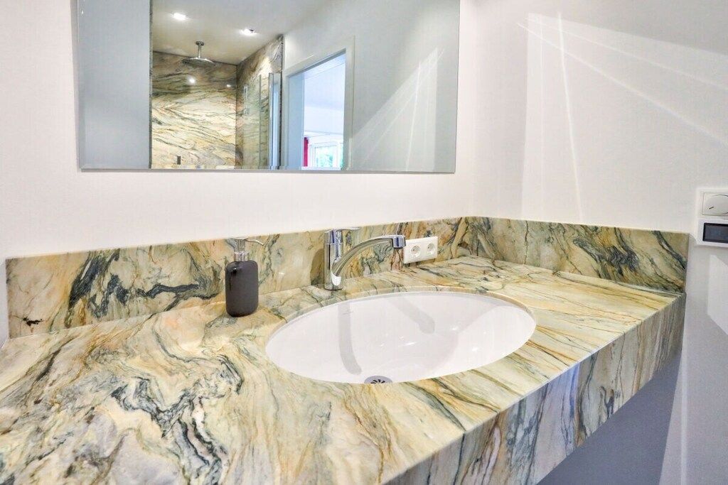 Un baño con lavamanos de mármol y un espejo encima.