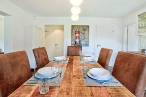 Een eetruimte met een houten tafel gedekt voor zes personen, omringd door bruine gestoffeerde stoelen.