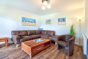 Ein Wohnzimmer mit einem Ecksofa, einem Couchtisch und einer Stehlampe.