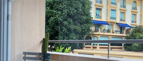 A balcony with a table and chairs, a striped towel, and a potted plant.