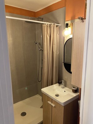Ein Badezimmer mit Dusche, Waschbecken und Spiegel.