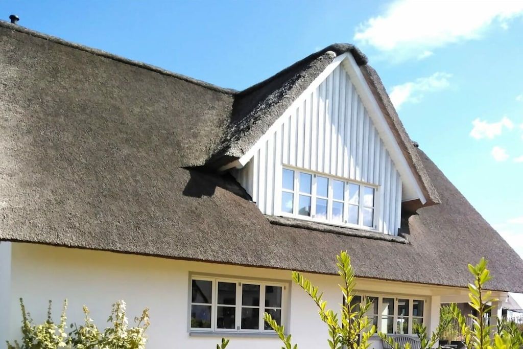 Ein Haus mit einem Strohdach und einem weißen Fenster.
