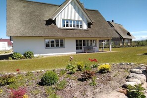 A house with a thatched roof, white walls, and a small porch. - Holiday home with 4 bedrooms (Gross Schwansee)