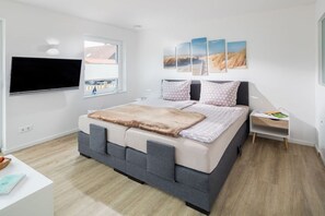 Ein modernes Schlafzimmer mit einem Bett, einem Flachbildfernseher, Kunstwerken und einem kleinen Nachttisch.