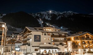 A multi-story hotel with a ski resort backdrop, featuring balconies and a prominent sign.