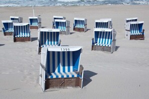 Strandstühle mit Nummern auf einem Sandstrand.