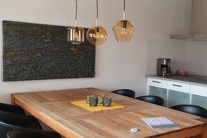 Un coin repas avec une table en bois, des chaises noires, un set de table jaune et de la verrerie décorative.