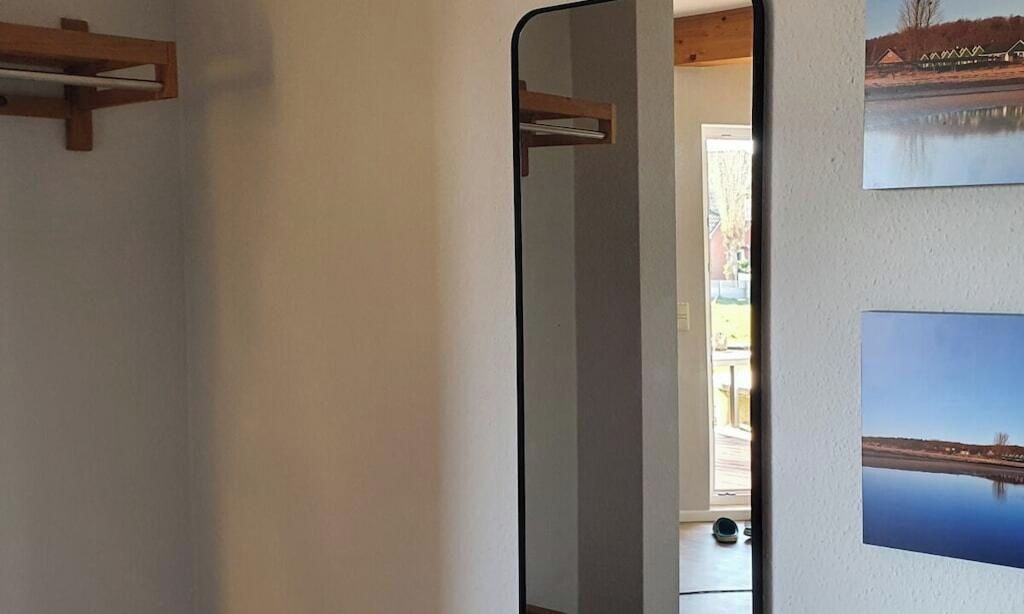A room with a wooden shelf, a mirror, and two framed pictures on the wall.
