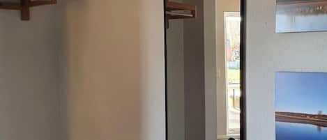 A room with a wooden shelf, a mirror, and two framed pictures on the wall.