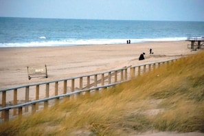 A beach with a wooden sign, a metal railing, and the ocean in the background. - Theodor-Heuss-Str. Holiday Apartment 11 (Westerland)