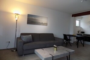A modern living room with a grey sofa, a coffee table, a floor lamp, and a painting on the wall. - Theodor-Heuss-Str. Holiday Apartment 11 (Westerland)