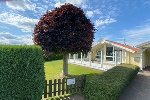 A building with a glass facade, a fenced yard, and a well-maintained hedge. - Holiday home with 2 bedrooms (Schönhagen)