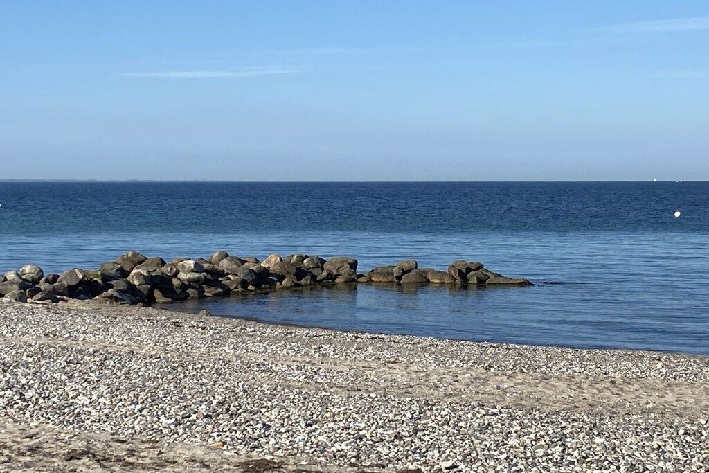 Een kiezelstrand met een rotsenrijke zeewering die zich in de zee uitstrekt.