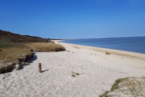 Ein sandiger Strand mit klarem Himmel und ruhiger See.