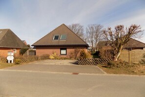 Ein Wohnhaus mit befestigter Auffahrt, einer Ziegelhausfassade und einem Holzzaun.