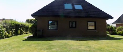 A single-story house with a sloped roof, two windows, and a small front yard.