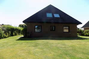 A single-story house with a sloped roof, two windows, and a small front yard. - Ground floor holiday apartment Zur Eiche 19 (Tinnum \/ Sylt)